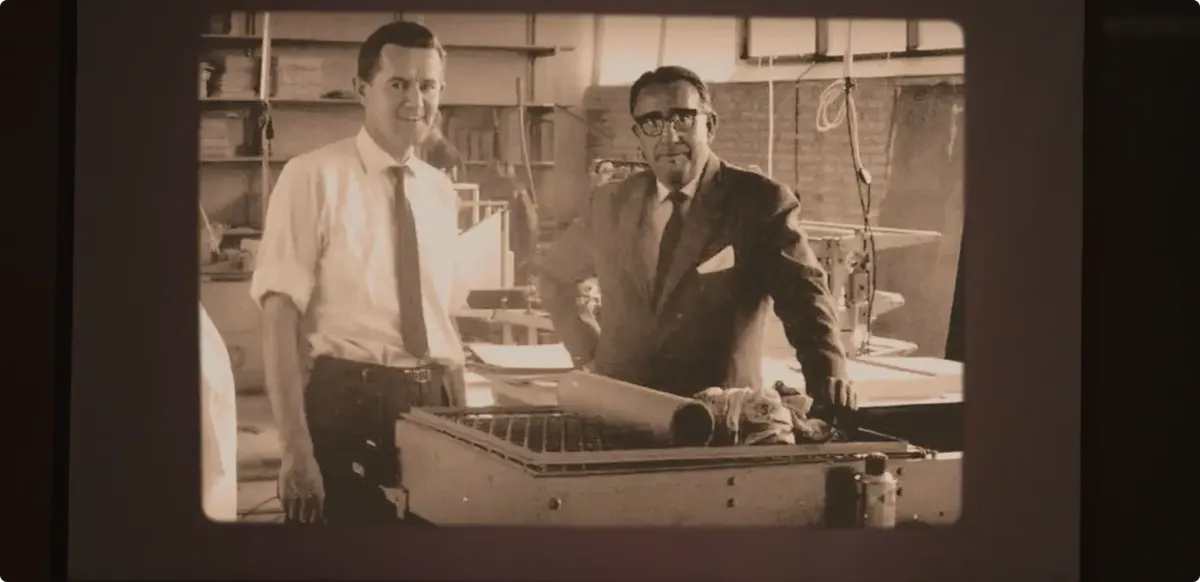 Aage Louis-Hansen standing with a colleague in front of machinery, in a factory setting in the 1960s.